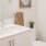 Large well lit bathroom with large mirror and white cabinets with a spacious walk in closet.